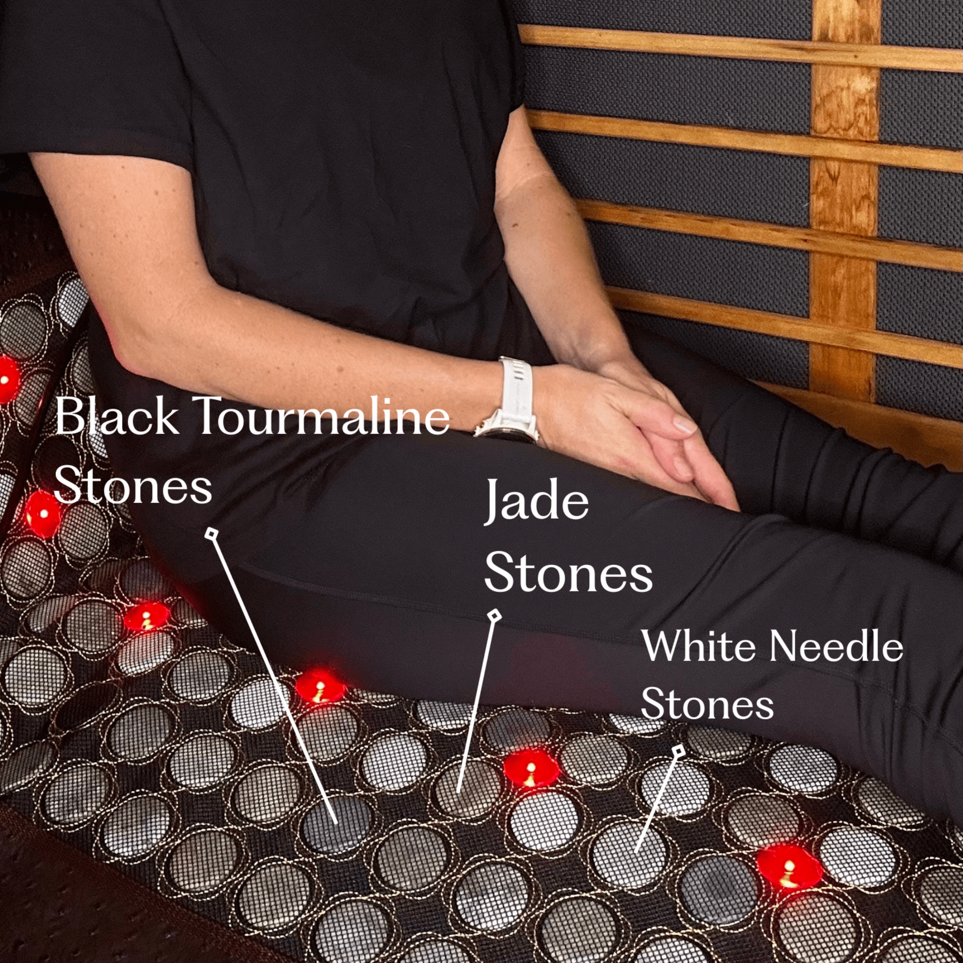 Person sitting on a mat with labeled stones including Black Tourmaline, Jade, and White Needle stones.