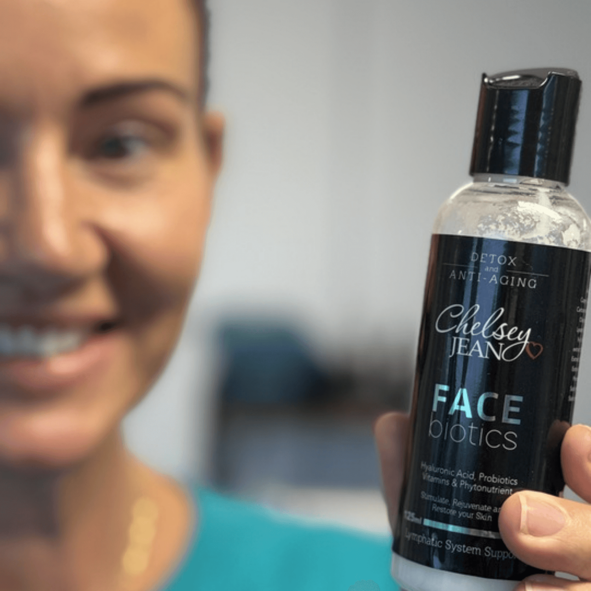 Person holding a bottle of Chelsey Jean Face Biotics product with a blurred background