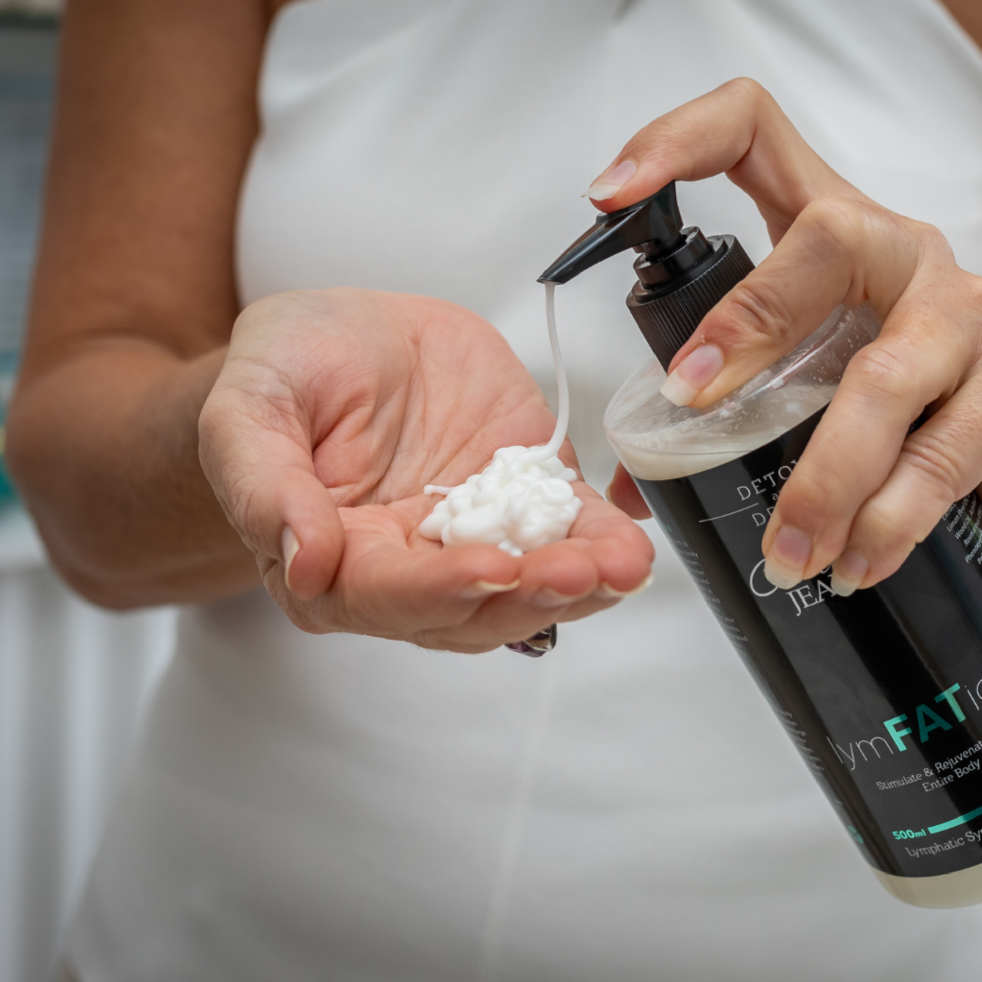 Person holding a bottle of skincare product and applying it to their hand.